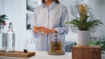 Hands holding tea cup in cozy kitchen. Peaceful woman enjoying home weekend