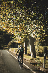 A woman cyclist training on a lonely road on a sunny day wearing a black jersey and bib shorts and...
