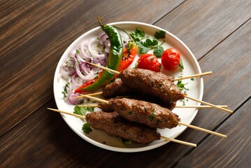 Homemade lula kebab with vegetables on wooden table