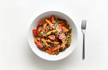 Bowl of bolognese penne pasta with minced meat, tomatoes and greens