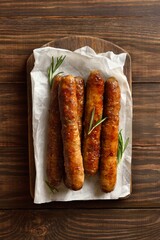 Roasted juicy sausages on wooden background