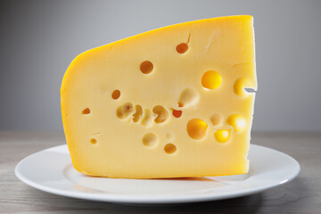 maasdam cheese on a plate, grey background