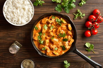 Chicken tikka masala curry in cast iron pan and bowl of rice