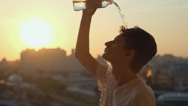 Tired of the heat, a man pours water from a bottle on his head
