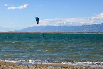 Kitesurfer is riding a wave on a sunny day with blue sky