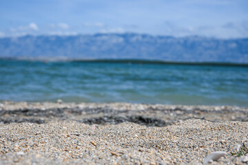 Fine gravel beach with blurred ocean and mountains providing a serene background
