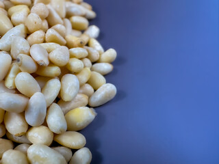 Background texture of shelled pine nuts and a gray-blue background.