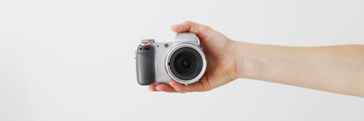 A person is holding a camera with a lens. The camera is silver and black