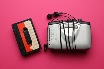 A cassette tape and a portable music player are on a pink background. Concept of nostalgia and the...