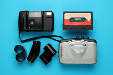 A camera, a cassette tape, and a roll of film are displayed on a blue background