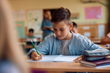 Happy schoolboy writing  test in  classroom.