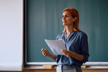Happy teacher giving  lecture in classroom.