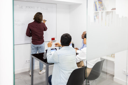 Team discussing and writing on whiteboard in English class