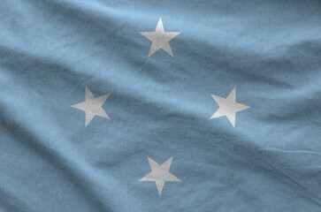 Micronesia flag depicted on folded wavy fabric of old cloth close up