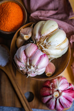 Whole garlic in a bowl and spices in a rustic setting