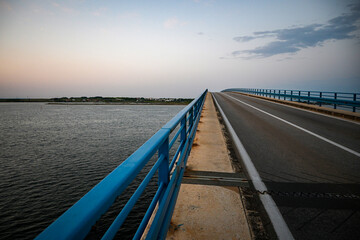 Fototapeta premium Bridge with blue railings leading to island at dusk