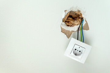 Damaged electrical socket hanging from wall. Home insurance for emergency failures repairs. Copy...