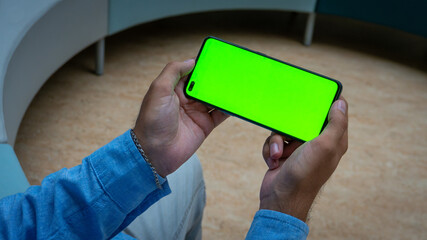 person holding a smartphone with green screen