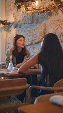 Friendly couple gossiping restaurant. Two women talking sharing news vertically 