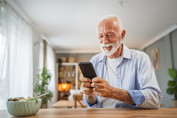 Senior man use a mobile phone while eat salad at home