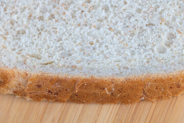 Close-up of the edge and texture of white bread slice on wooden table