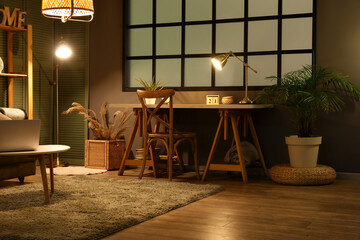 Wooden table, chair and glowing lamp in interior of living room