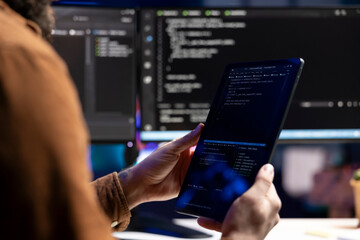 Computer scientist doing software quality assurance using tablet, reading source code before...