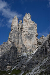 Massive, impressive mountains tower into a blue summer sky, showcasing the grandeur and beauty of the alpine landscape.