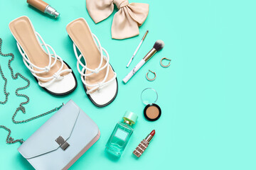 Stylish heeled sandals, bag, accessories and makeup brushes on turquoise background