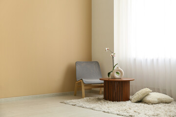 Coffee table with orchid flower, chair and carpet with cushions near light curtain in room