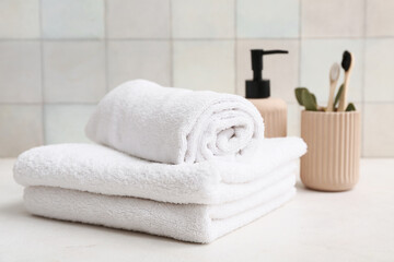 Clean soft towels, bottle of liquid soap and holder with toothbrushes in bathroom, closeup