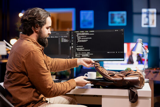 Programmer packing laptop at end of work shift after securing company servers from virus attacks. Man putting notebook in backpack, leaving office after building firewalls protecting data - Powered by Adobe