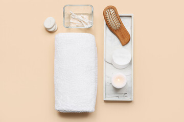 Composition with rolled soft towel, stone tray, cotton pads and candle on beige background