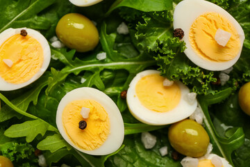 Healthy salad with quail eggs, arugula and olives as background, closeup