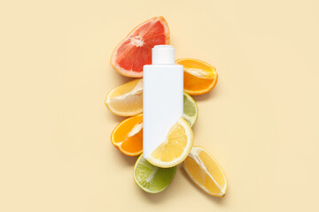 Composition with pieces of citrus fruits and bottle of cosmetic product on yellow background