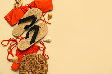 Flip flops with swimsuit, straw bag and seashells on beige background