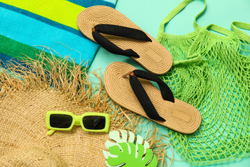Flip flops with string bag, towel, sunglasses and straw hat on turquoise background © Pixel-Shot