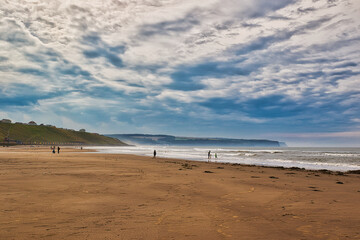 Serene Beach Scene with People Walking Along the Shore in Whitby, North Yorkshire
