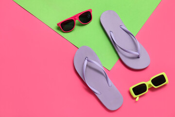 Flip flops with sunglasses on color background