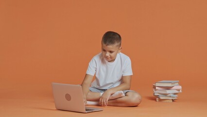 A young schoolboy typing on a laptop keyboard