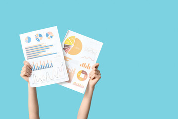 Female hands with financial graphics on blue background