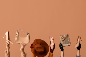 Female hands in gloves with bags, hat and heeled shoes on beige background