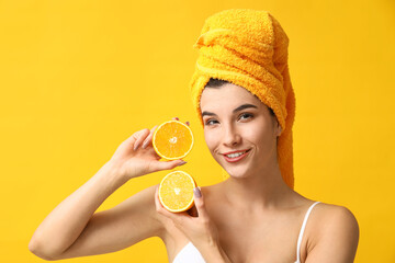 Beautiful young woman with orange on color background