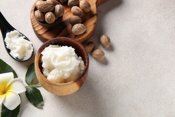 Bowl and spoon of shea butter with nuts on white background
