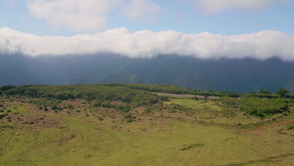 Fototapeta premium Scenic mountains covered clouds with asphalt road drone view. Green valley