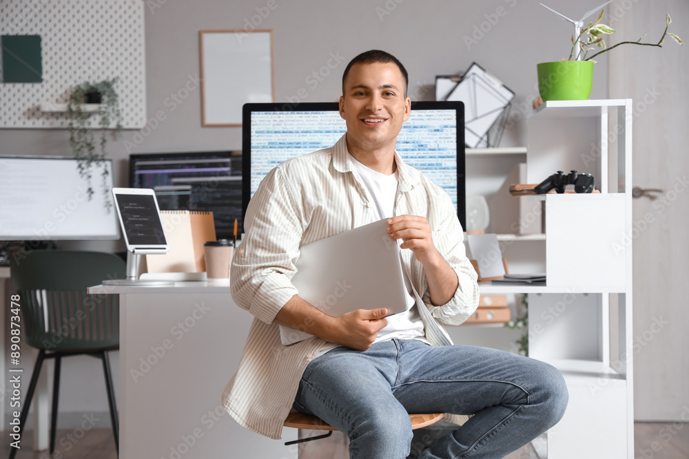 Poster handsome programmer with laptop sitting in office