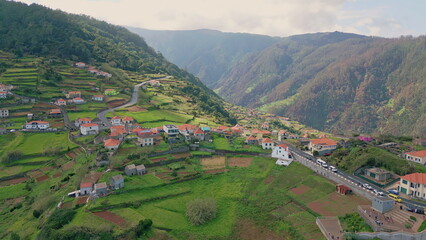 Scenic village nestled green hills creating tranquil landscape drone view.
