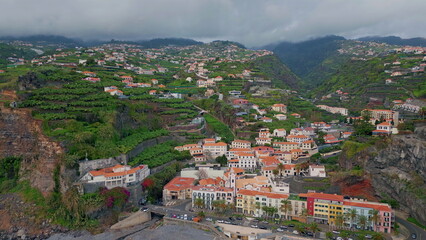 Fototapeta premium Aerial beautiful coastal settlement with terraced hills and green fields. 