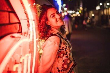 Fototapeta premium Woman Posing by Neon Lights in a Night Cityscape