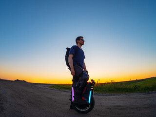 The guy uses a monowheel for trips to nature. Electric motor wheel . Portrait at sunset © pavelkant